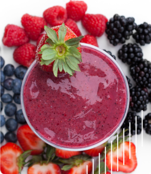 A glass of mixed berry smoothie garnished with a strawberry, surrounded by fresh raspberries, blackberries, blueberries, and sliced strawberries.